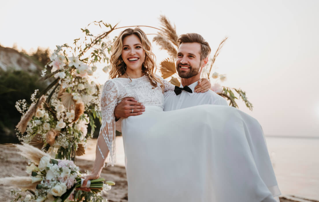 Novio cargando a la novia en la playa
